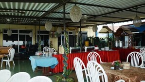 An outdoor dining area with tables covered in red and blue tablecloths, white chairs, and hanging decorative lights. - Hotel Marcopolo (Bandar Lampung)