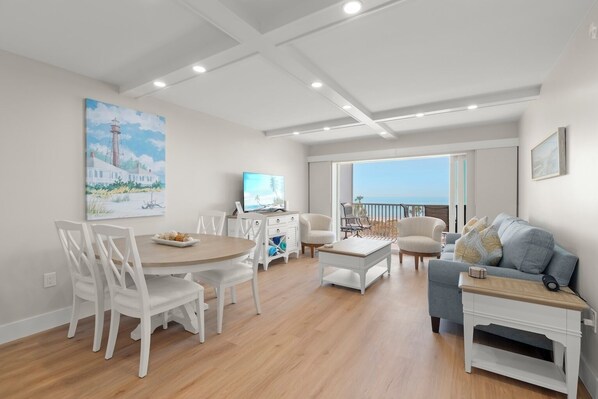 Una sala de estar moderna con comedor, televisor y balcón con vistas.