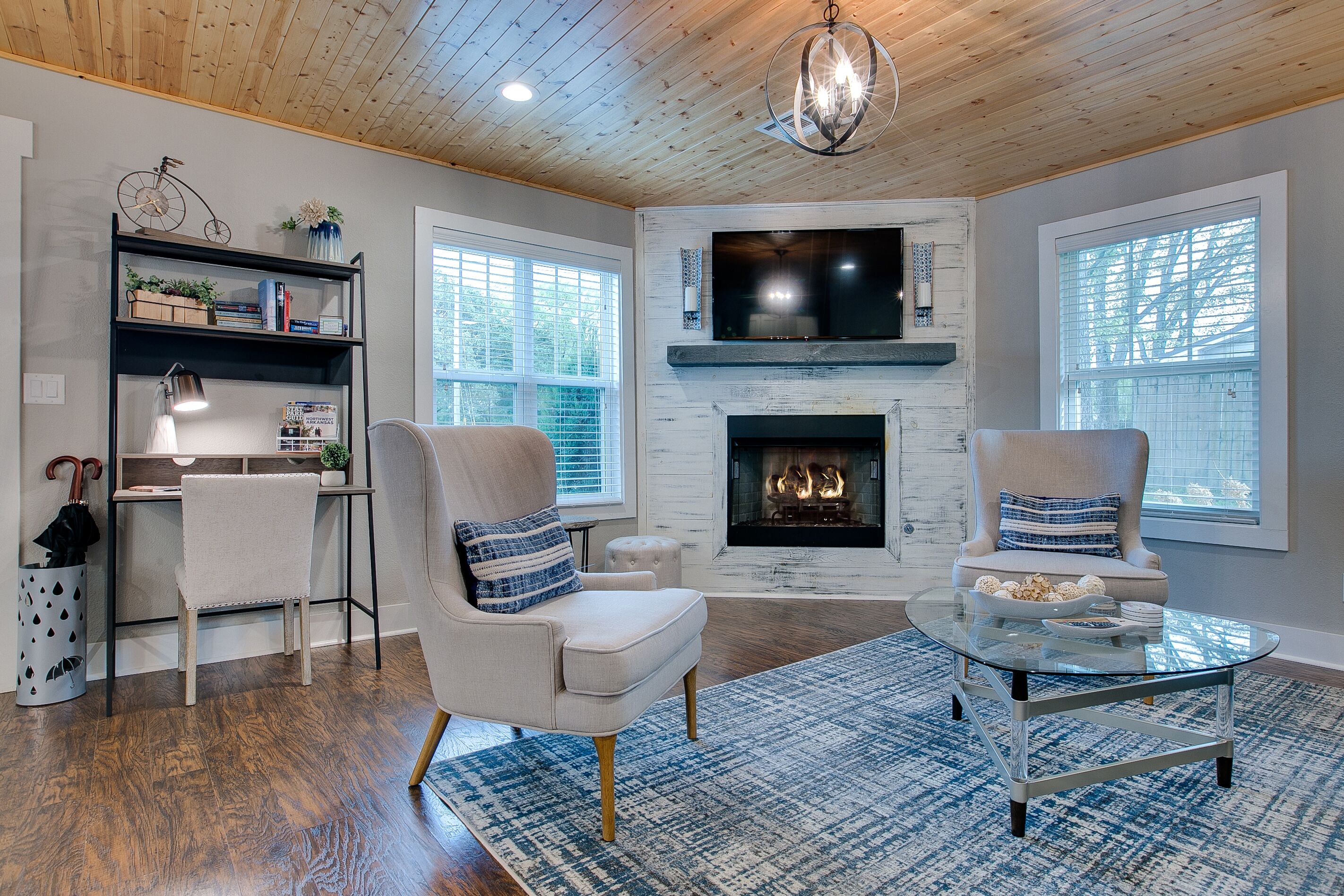 A living room with a fireplace, two armchairs, a coffee table, and a bookshelf.