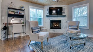Una sala de estar con chimenea, dos sillones, una mesa de centro y una estantería.