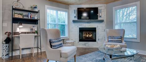 A living room with a fireplace, two armchairs, a coffee table, and a bookshelf.