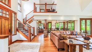 A spacious living area with a wooden staircase, a leather sofa, and a dining table.