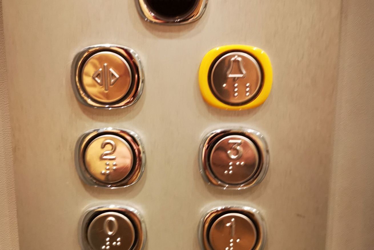 Primer plano de un panel de control de ascensor con botones numerados del 0 al 3 y un botón de timbre.