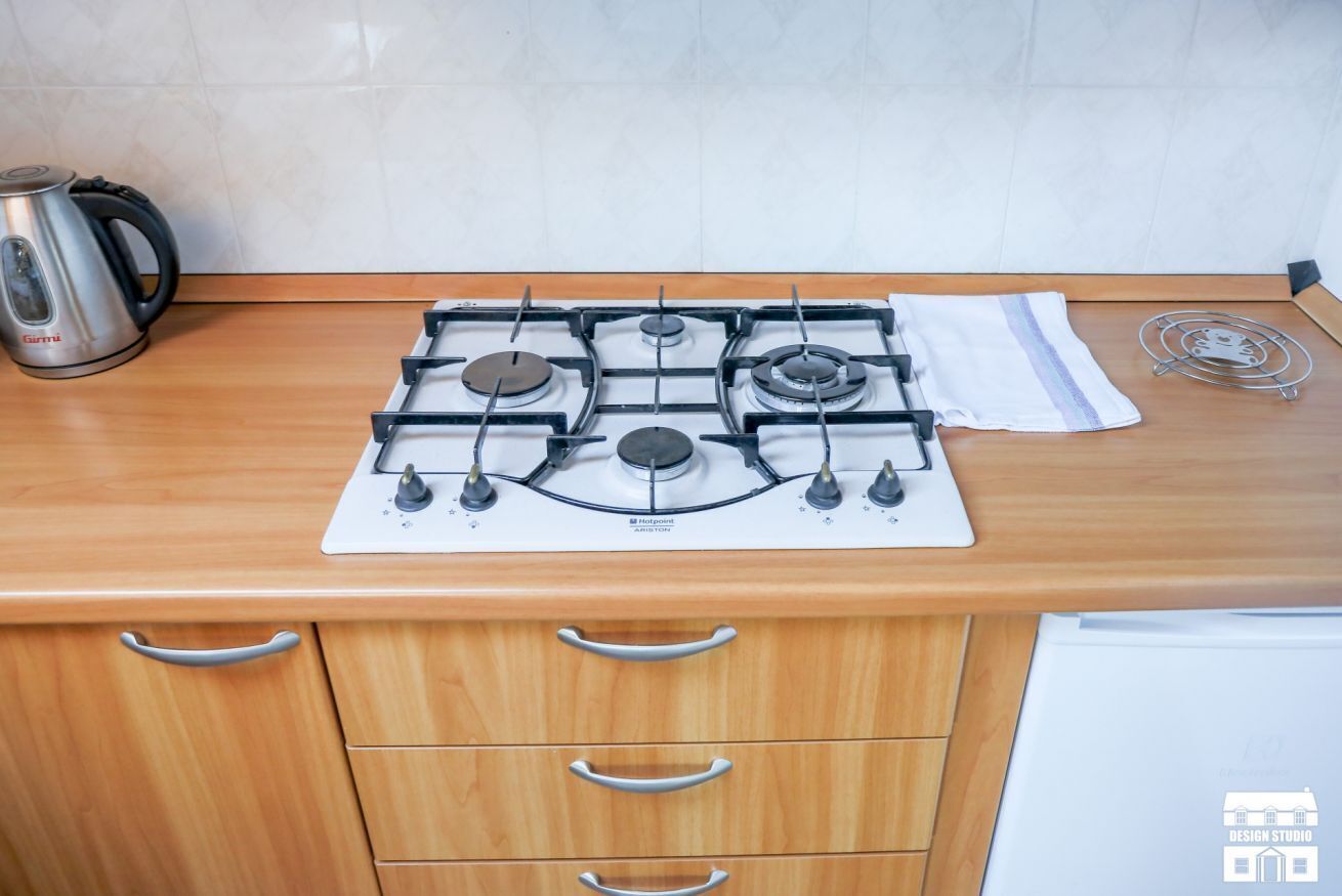 Une cuisine équipée d’une cuisinière à gaz, d’une bouilloire et d’un égouttoir à vaisselle.