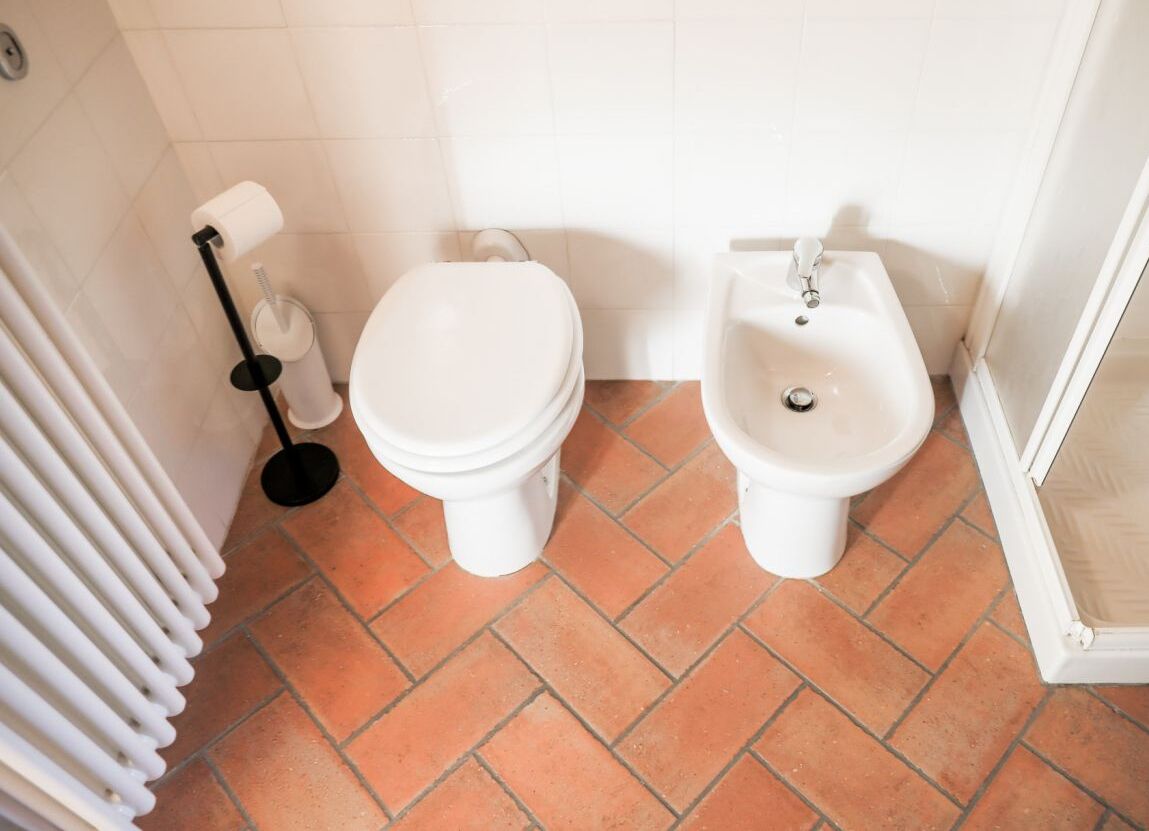 A bathroom with a toilet, bidet, and radiator.