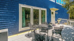 A blue house with a deck, a table, and chairs.