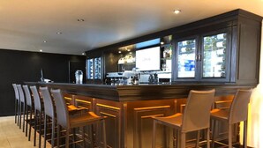 Een bar met een lange toonbank, meerdere barstoelen en een groot scherm waarop het L'Oreal logo staat.