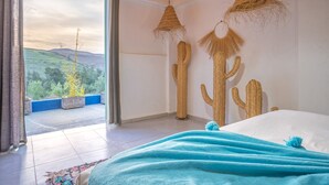 Une chambre avec un grand lit, une vue sur l’extérieur et deux lampes suspendues.