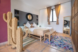 Quarto com cama, espelho, guarda-roupa e uma planta de cacto.