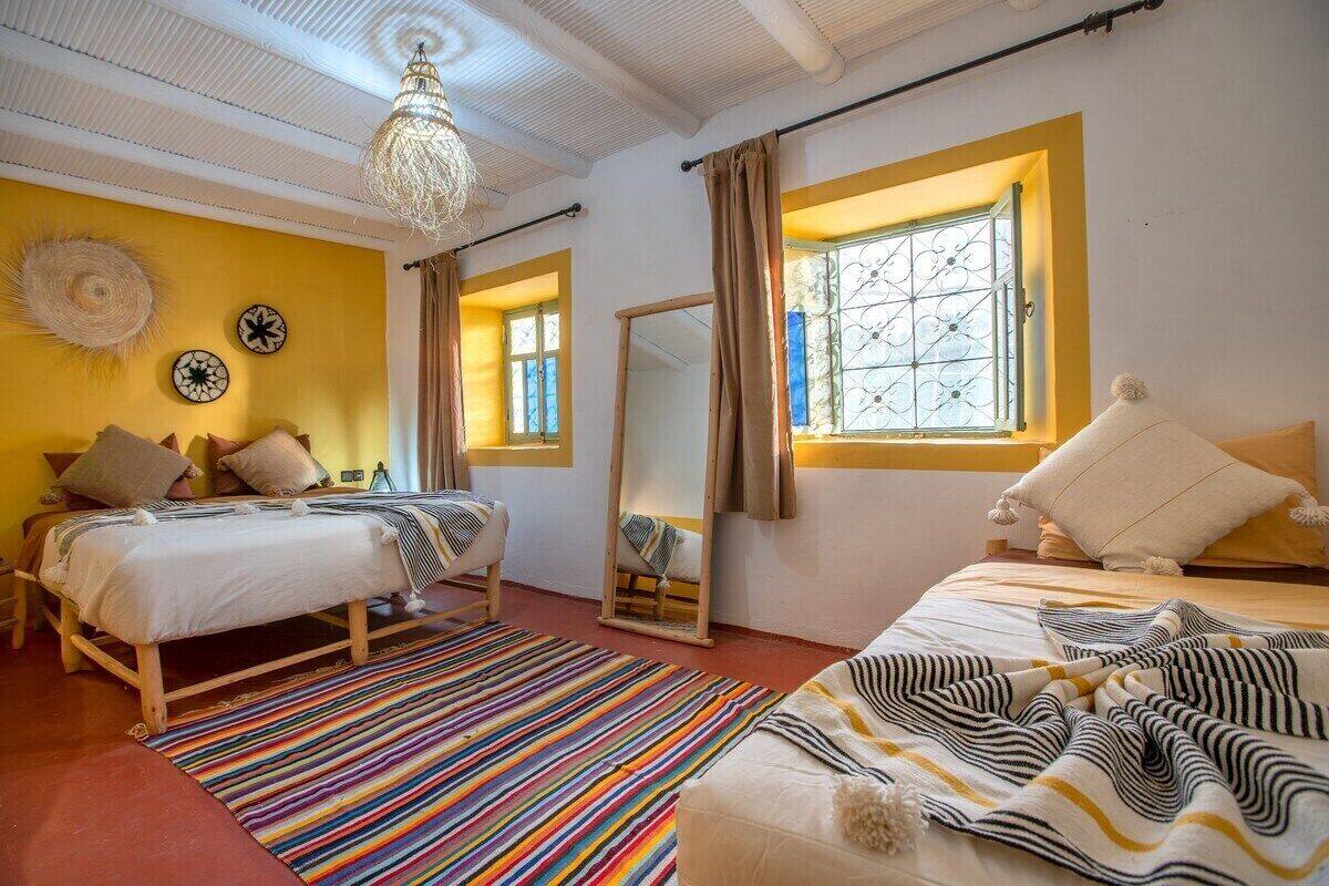 Une chambre avec deux lits, un grand miroir et un tapis rayé aux couleurs vives.