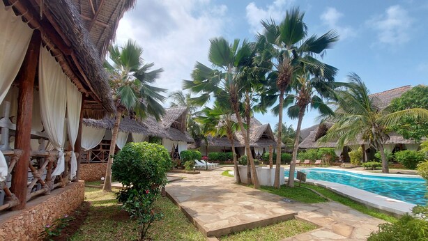 A resort with thatched-roof huts, a swimming pool, and palm trees. - Sofia House (Malindi)