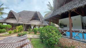 A resort with thatched-roof structures, a pool, and wooden seating areas. - Sofia House (Malindi)
