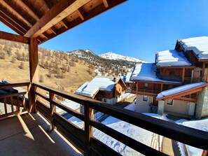 A wooden balcony with a view of snow-covered buildings and mountains. - 200m from shops, 4th floor, swimming pool, balcony, parking, tv, ski locker, 50m², Vars (Vars)