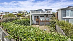 A modern two-story house with a covered patio, surrounded by lush greenery and neighboring houses. - RELAX @ Sea La Vie KIAMA Million Dollar Views (Kiama)