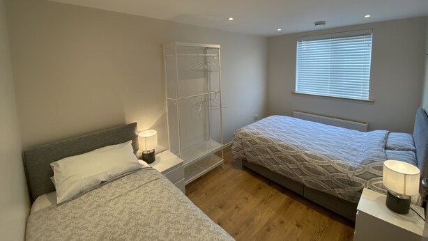 Ein Schlafzimmer mit zwei Betten, einem Kleiderschrank, einem Fenster mit Jalousien und einer Heizung.