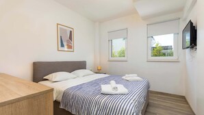 A modern hotel room with a bed, a desk, and a TV. - Villa Riviera (Sveti Lovrec Labinski)