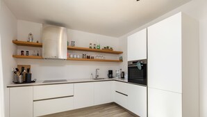 A modern kitchen with white cabinets, wooden shelves, and a stainless steel range hood. - Villa Riviera (Sveti Lovrec Labinski)