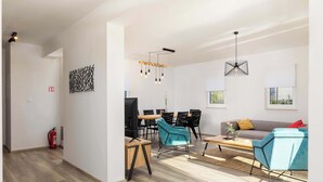 A modern living room with a sofa, chairs, a coffee table, and a dining area. There is a fire extinguisher on the wall and a ceiling light fixture. - Villa Riviera (Sveti Lovrec Labinski)