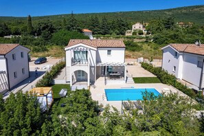 Il s’agit d’une propriété résidentielle dotée d’une piscine, d’un patio couvert et offrant une vue sur la végétation et les collines environnantes.