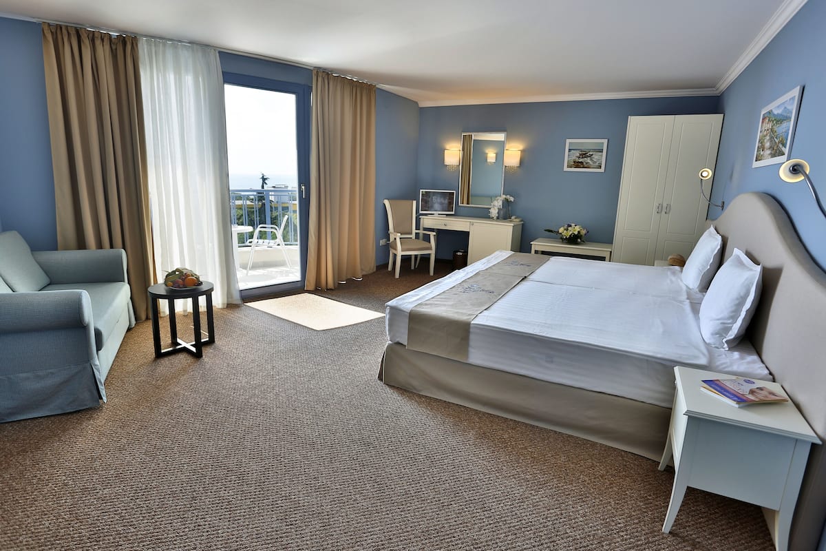 Une chambre d’hôtel comprenant un lit, un bureau, une chaise, une petite table, un canapé et une vue sur l’extérieur.