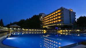 A hotel with a large swimming pool, multiple balconies, and a well-lit exterior. - Hotel Sofia - All Inclusive (Varna)