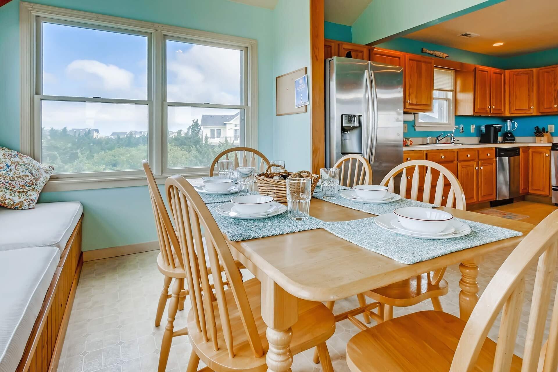 A dining area with a table set for four, wooden chairs, and a view of the city through large windows.