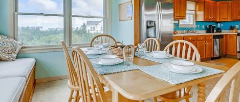 A dining area with a table set for four, wooden chairs, and a view of the city through large windows.