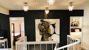 A modern interior with a staircase, a large abstract painting, and chandeliers.