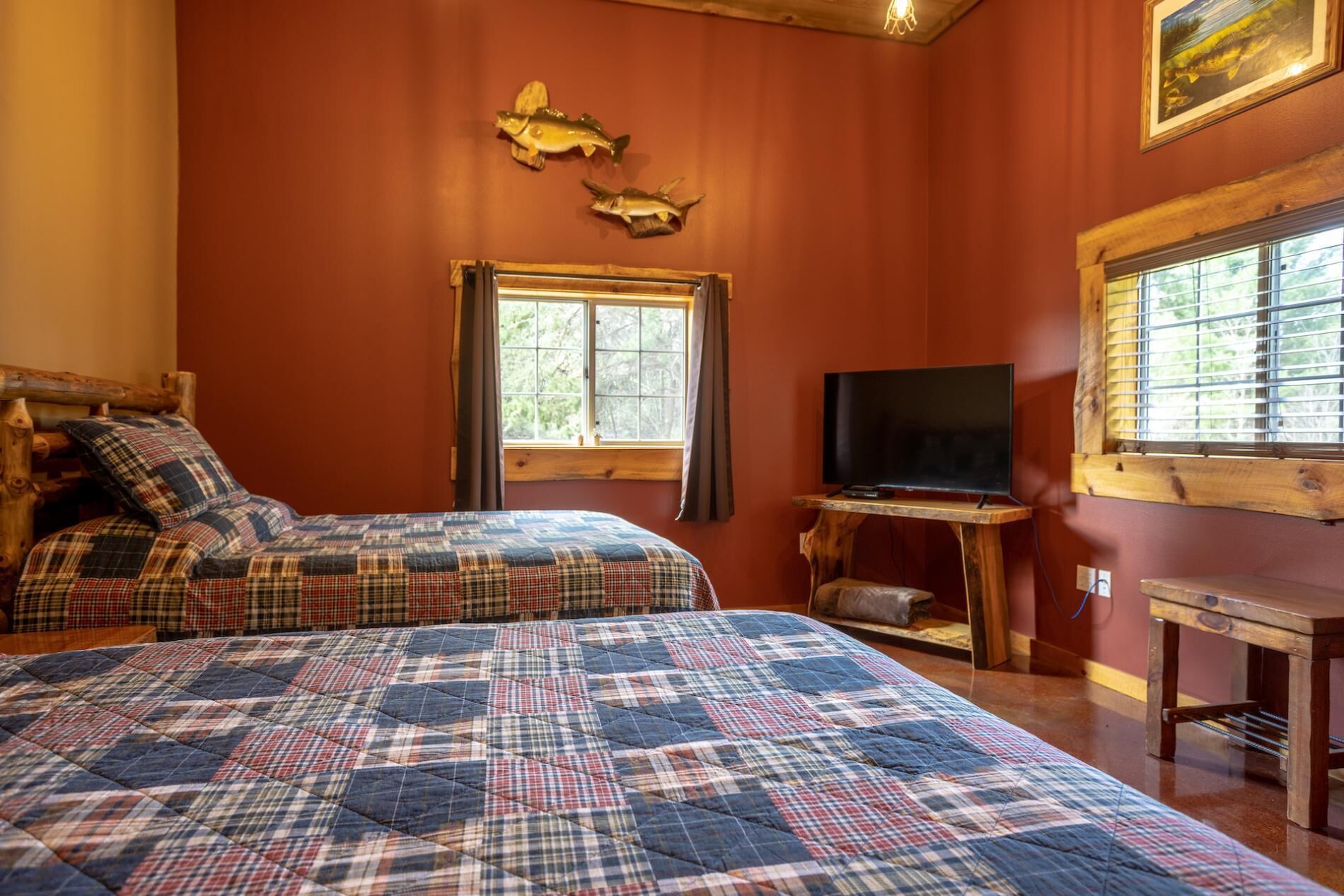 A cozy room with two beds, a television, and a window with blinds.