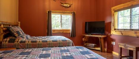 A cozy room with two beds, a television, and a window with blinds.