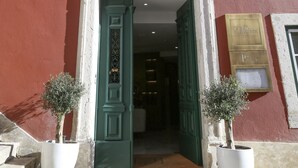 Un edificio de fachada roja, puerta verde y dos macetas.