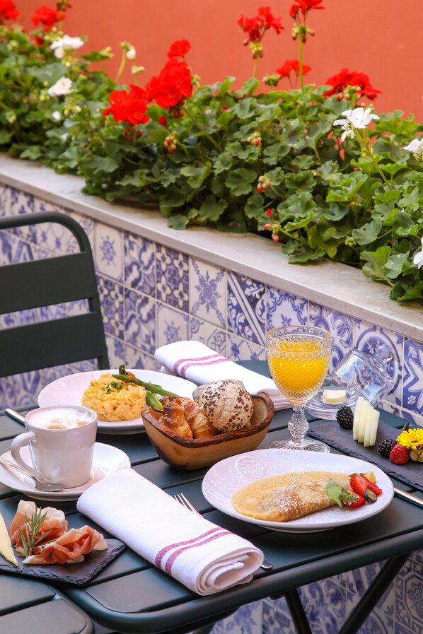 Una mesa dispuesta con alimentos para el desayuno, incluyendo cruasanes, un plato de comida, un vaso de zumo de naranja y una taza de café.