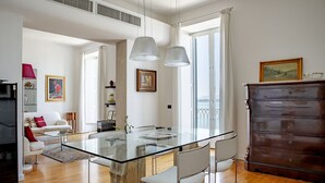 Un soggiorno moderno con tavolo da pranzo in vetro, divani bianchi e una cassettiera in legno.
