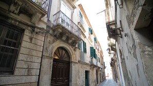 Una stretta via fiancheggiata da edifici storici, con un ingresso ad arco e balconi tradizionali.