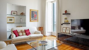 Un soggiorno moderno con un divano, un tavolino in vetro e una TV a schermo piatto.