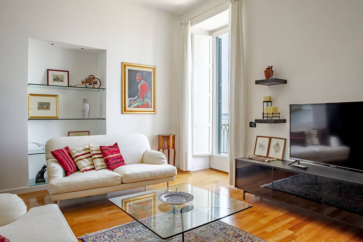 A modern living room with a sofa, glass coffee table, and a flat-screen TV.