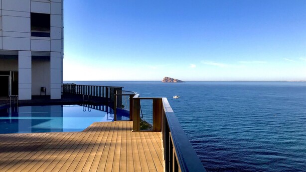 A pool area with a wooden deck and a view of the ocean. - MEDITERRANEAN VIEW BENIDORM R078 (Benidorm)