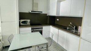 A modern kitchen with white cabinets, a microwave, an oven, and a stainless steel sink. - MEDITERRANEAN VIEW BENIDORM R078 (Benidorm)