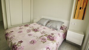A bedroom with a bed, a nightstand, a wardrobe, and a painting on the wall. - MEDITERRANEAN VIEW BENIDORM R078 (Benidorm)
