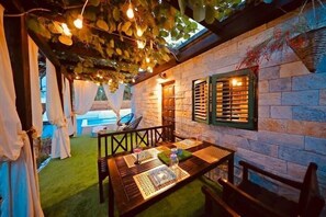 An outdoor seating area with a stone wall, a wooden table, and chairs.