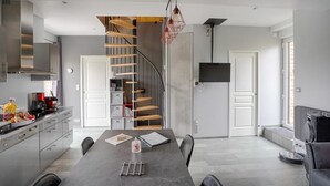 Una cocina moderna con una isla central, estufa integrada y un comedor con una mesa grande.