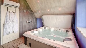 Un baño moderno con una bañera grande, un perchero con toallas blancas y un equipo de aire acondicionado.