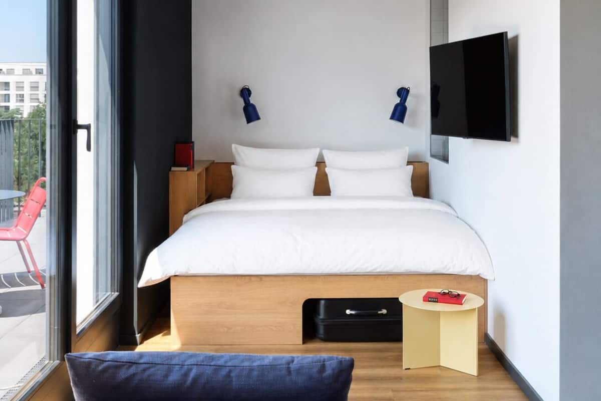 A modern hotel room with a large bed, a television, and a view of the outdoors.