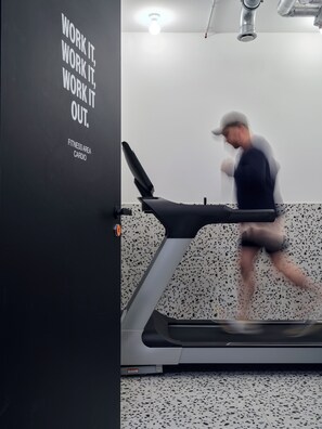 A treadmill in a fitness area with a motivational poster on the wall. - STAYERY Frankfurt Sachsenhausen (Frankfurt)