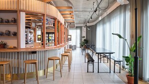 Un área de bar moderna con taburetes de madera, una mesa larga y plantas en macetas.