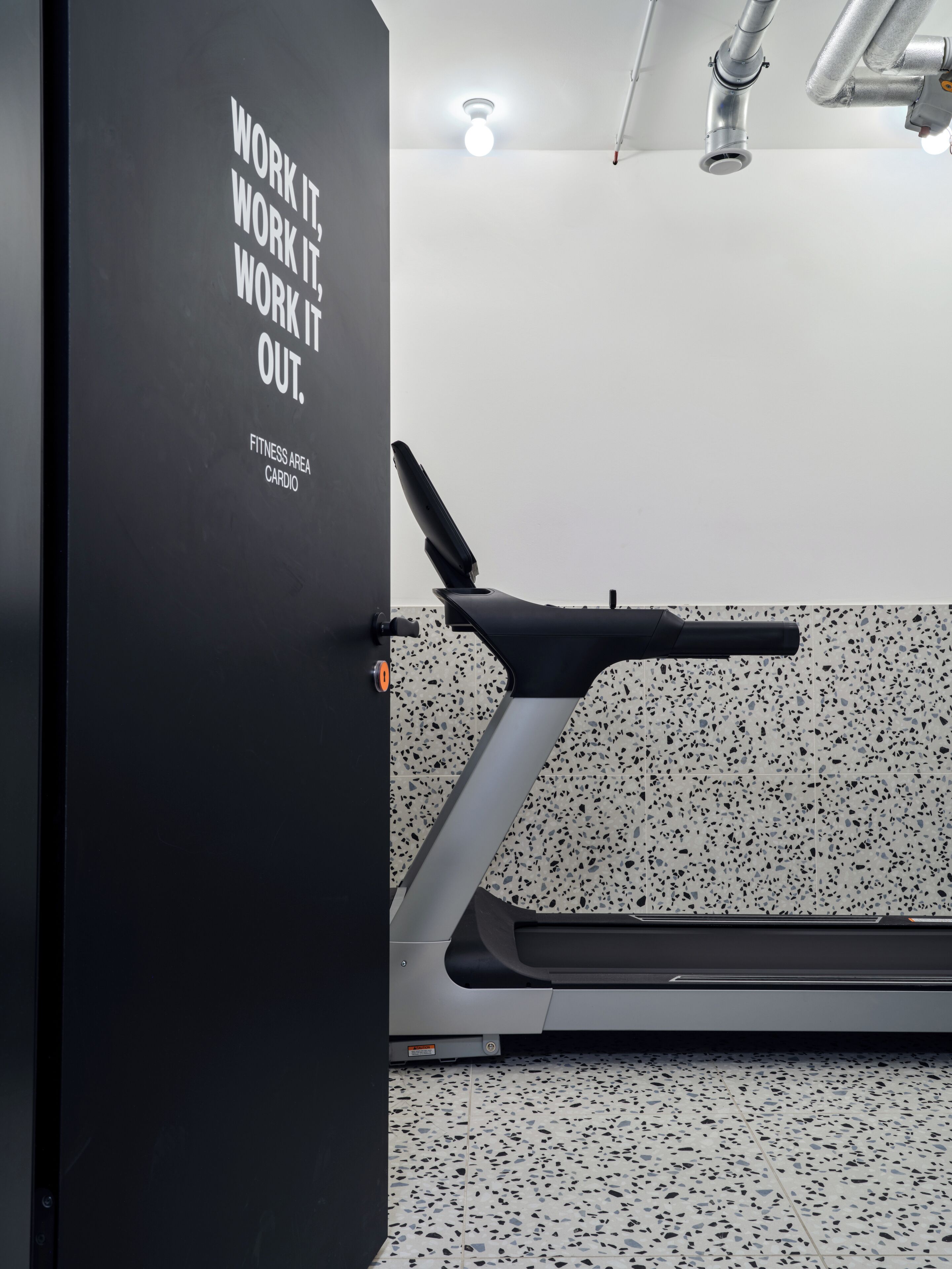 A fitness area with a treadmill and a motivational quote on the wall.