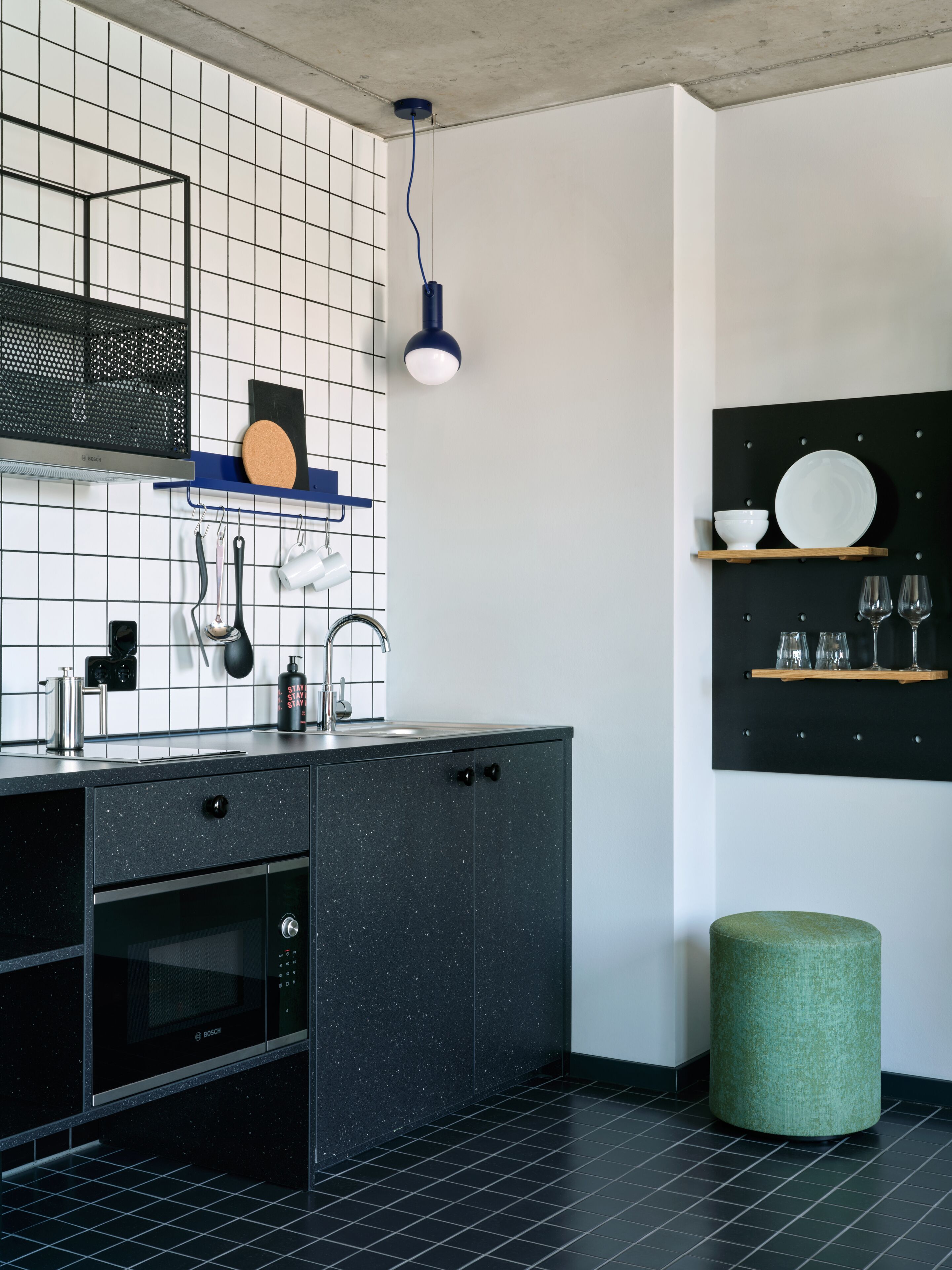 A modern kitchen with a black countertop, stainless steel appliances, and a grid-patterned backsplash.
