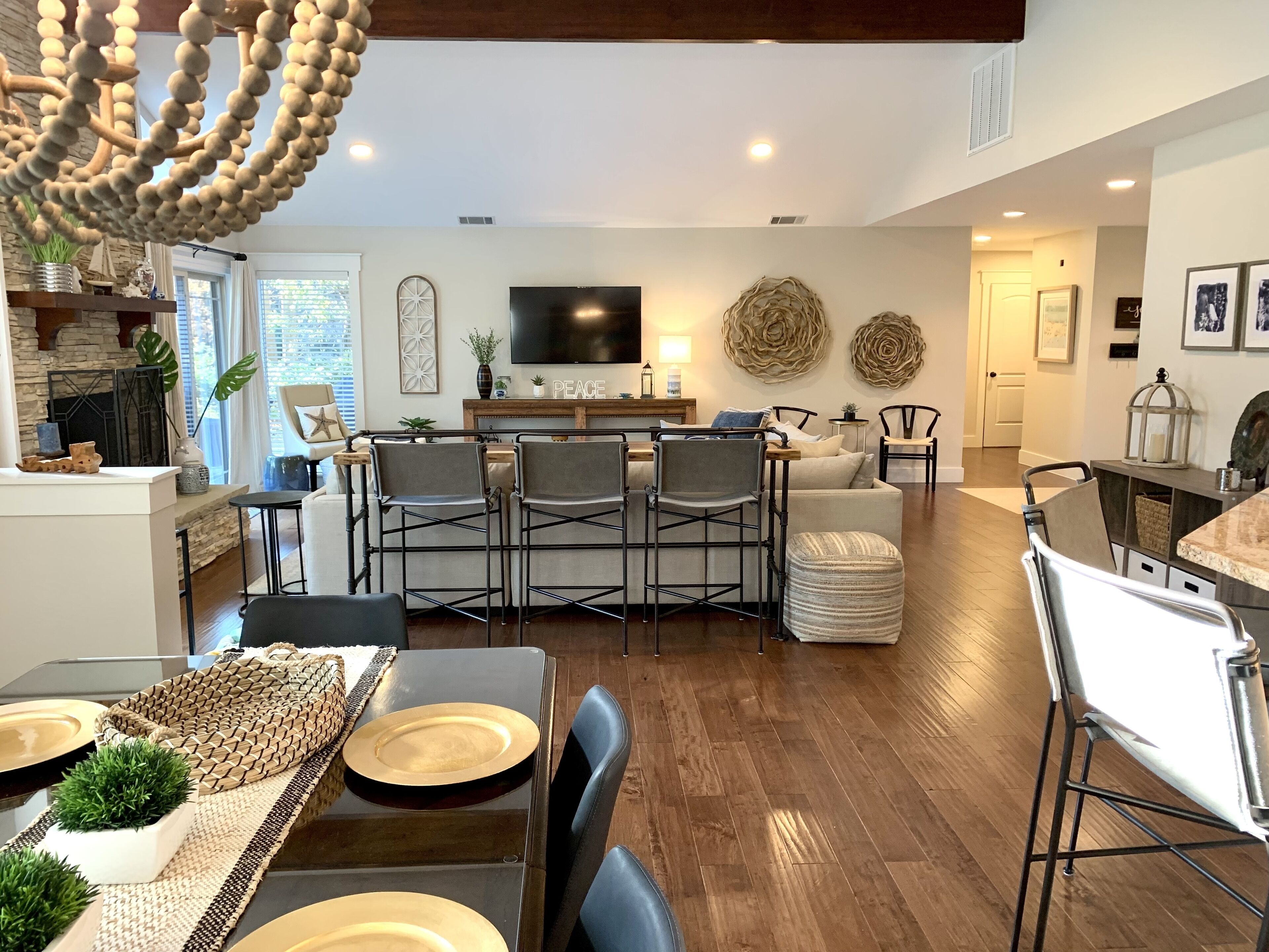 A modern living room with a dining area, wooden flooring, and a TV mounted on the wall.