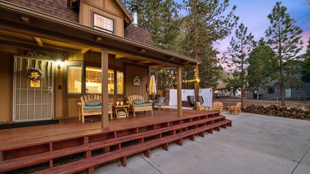 A wooden deck with outdoor seating, a covered porch, and a stone wall. - Walk to Bear Resort with Slope Views. Close to Zoo & Golf, Spa, BBQ & Arcade! (Big Bear Lake)