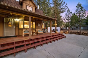 A wooden deck with outdoor seating, a covered porch, and a stone wall.